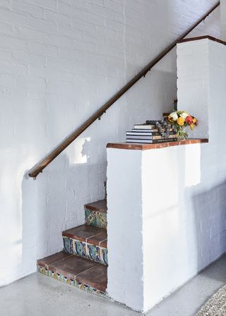 stairs with colorful tiles white walls and handrail
