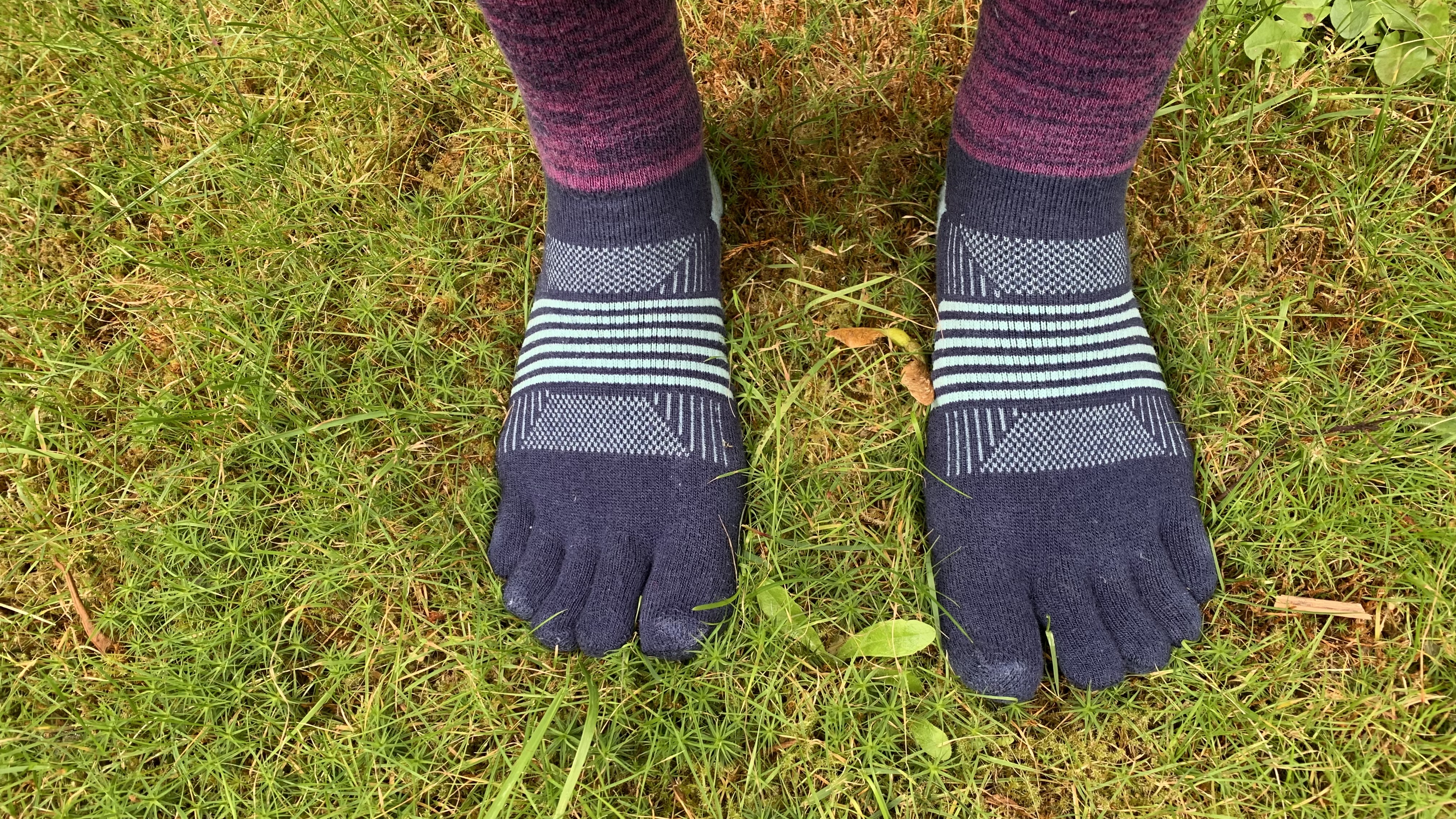 Feet standing in the grass wearing the Injinji Trail Midweight Crew toe socks
