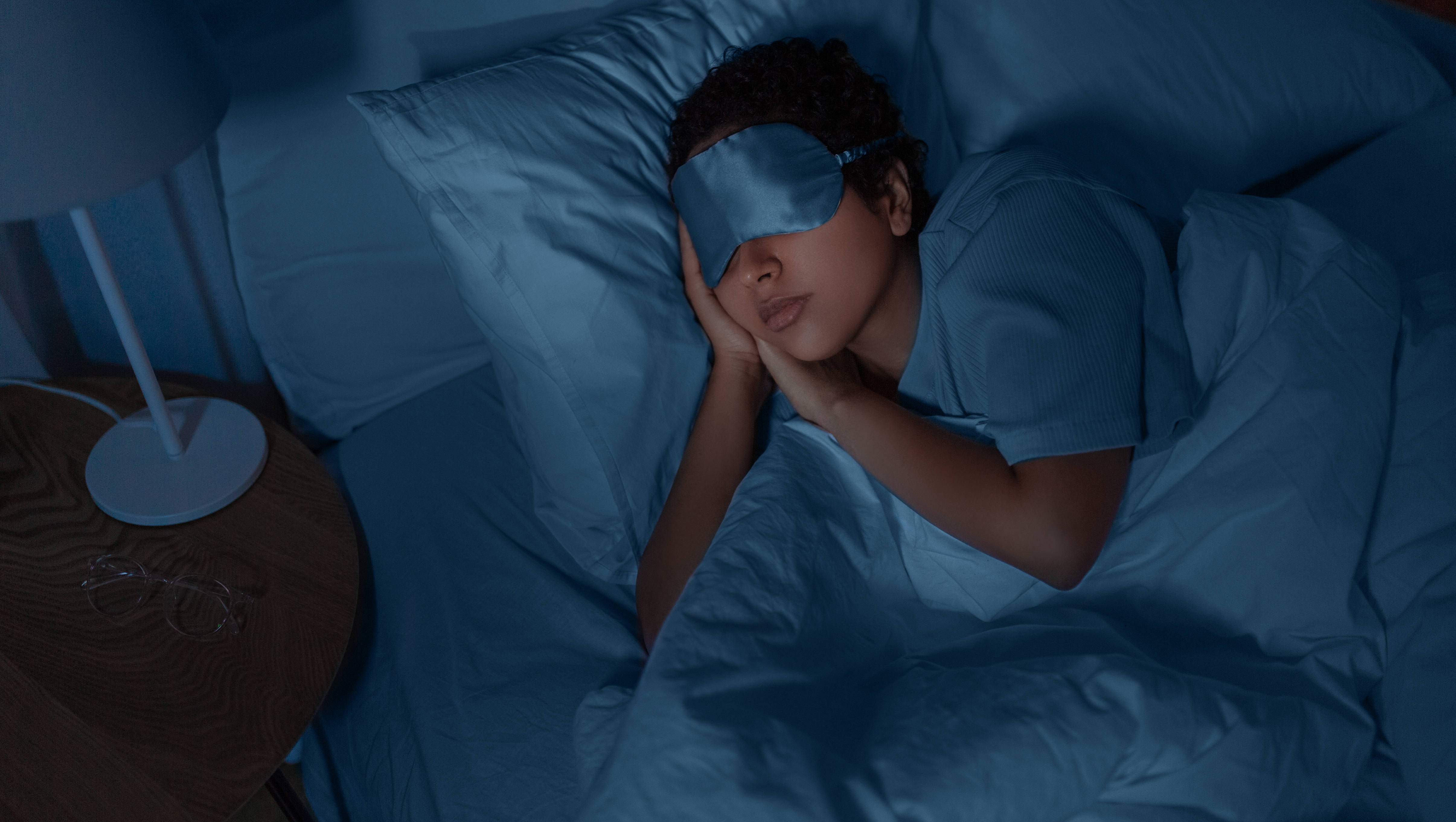 Женщина спит в постели с маской на лице