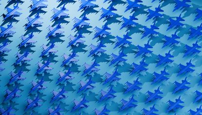 small models of blue jet fighter planes lined up in neat rows with a teal background