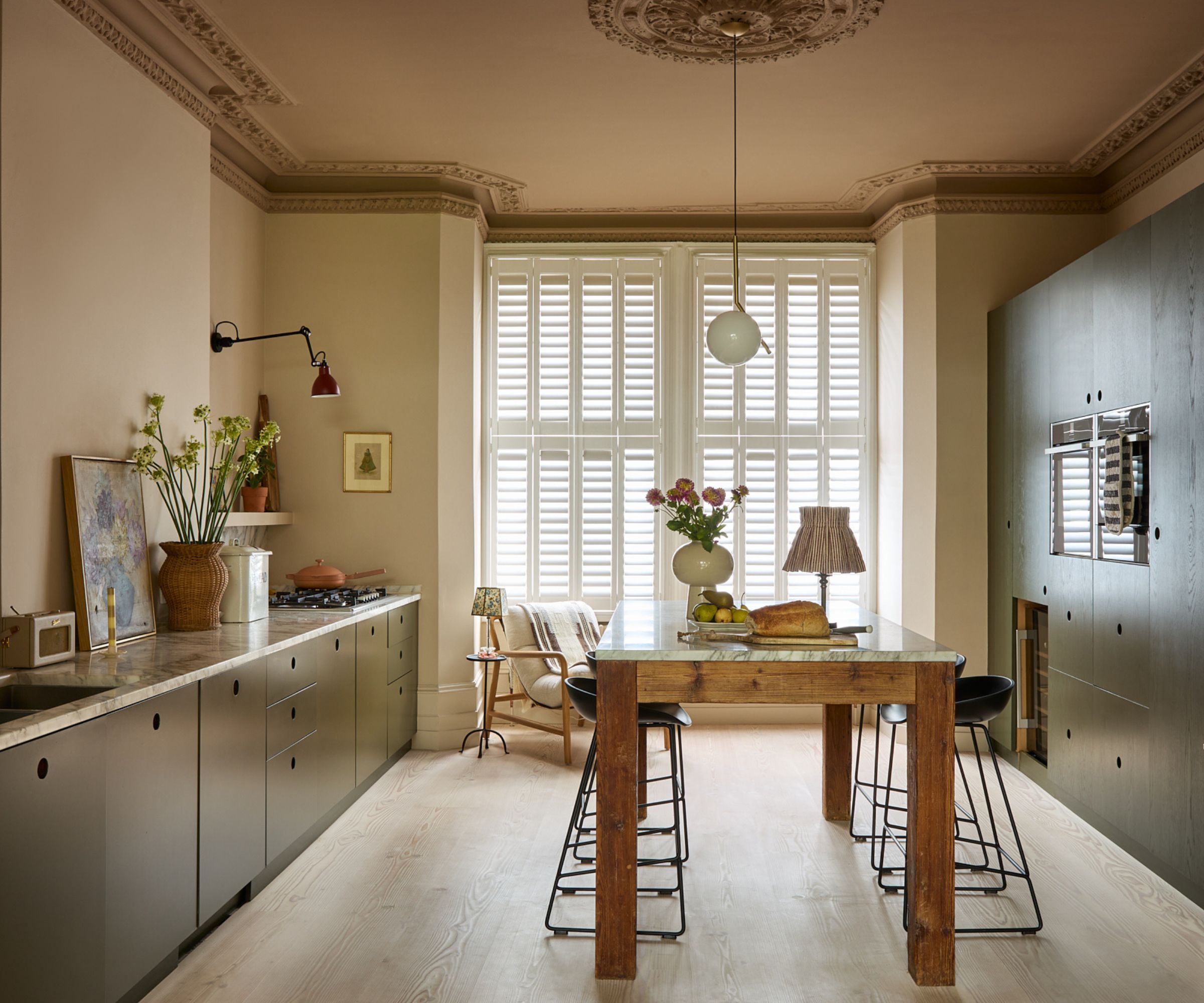 A galley kitchen with green cabinets and a freestanding wooden kitchen island