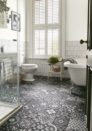 white bathroom with roll top bath, shutters, grey, black, white vinyl patterned flooring