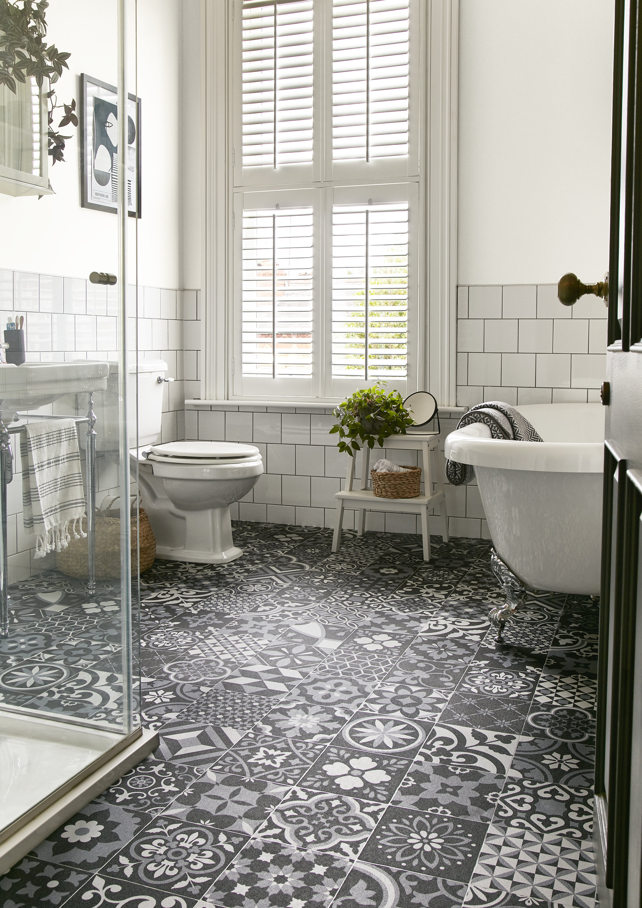salle de bain blanche avec baignoire sur roulettes, volets, sol gris, noir et blanc à motifs en vinyle