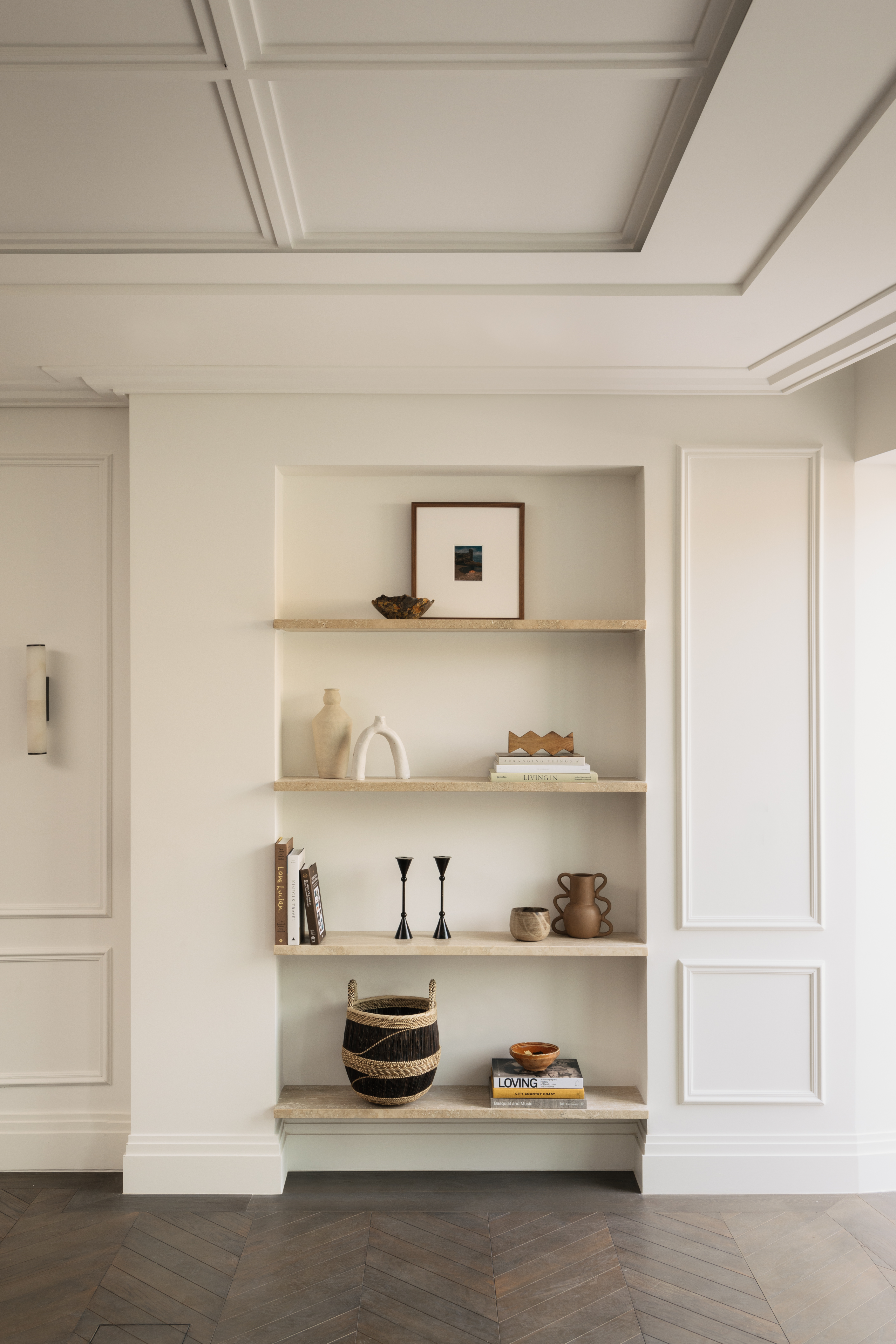 a panelled room, painted white, with open shelving with curated objects and art
