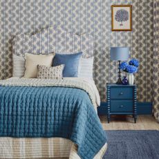 A bedroom with a patterned wallpaper matching the scalloped bed hadboard
