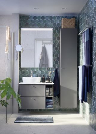 A blue bathroom with blue tiles in a neutral wet room with a wall hung basin unit and towel rail