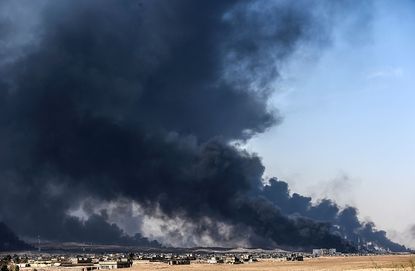 Smoke rises from burning oil wells near Mosul.