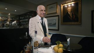 Alessandro Palazzi smiles while holding a drink over a trolley at Dukes Bar.