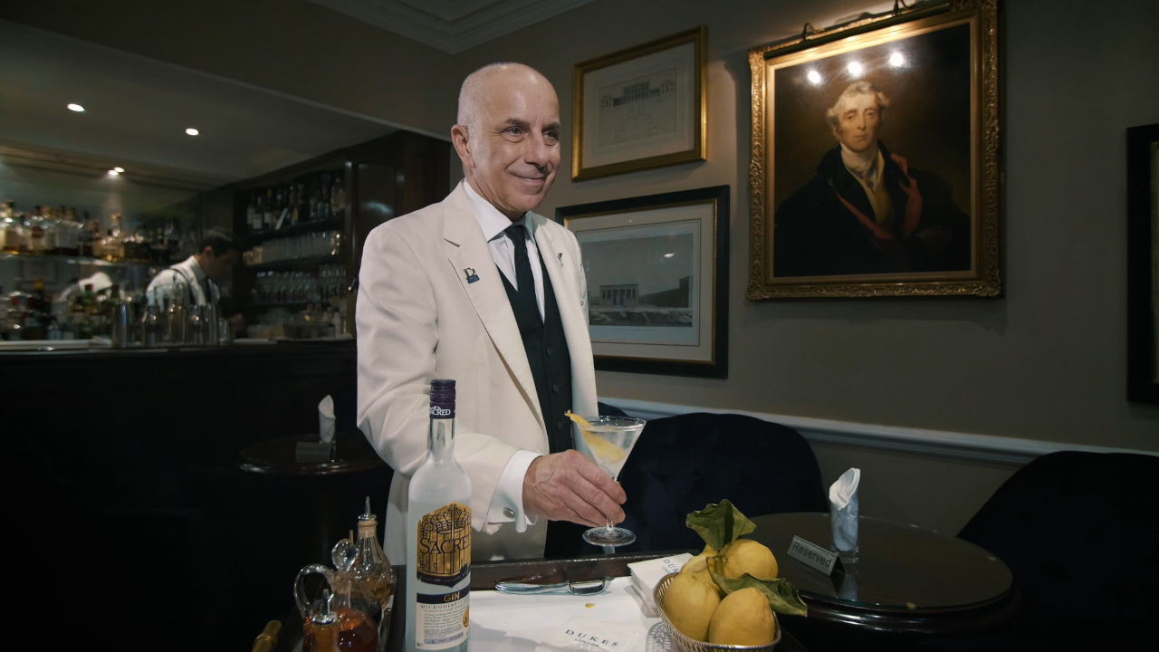 Alessandro Palazzi smiles as he holds a drink over a trolley at Dukes Bar.