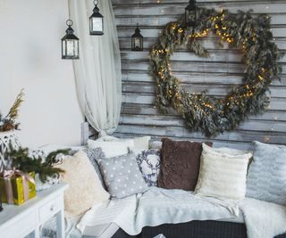 Sofa with knit blankets and cushions on home cozy terrace with Christmas decoration
