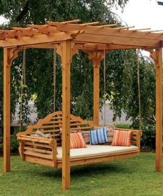 wooden pergola with hanging swing daybed and scatter cushions.