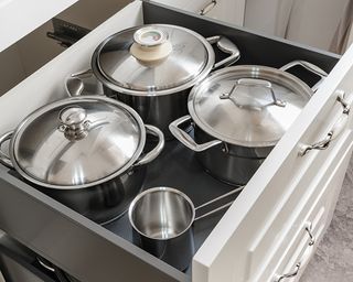 a selection of steel saucepans in a kitchen drawer, to show one of w&h's pan storage ideas