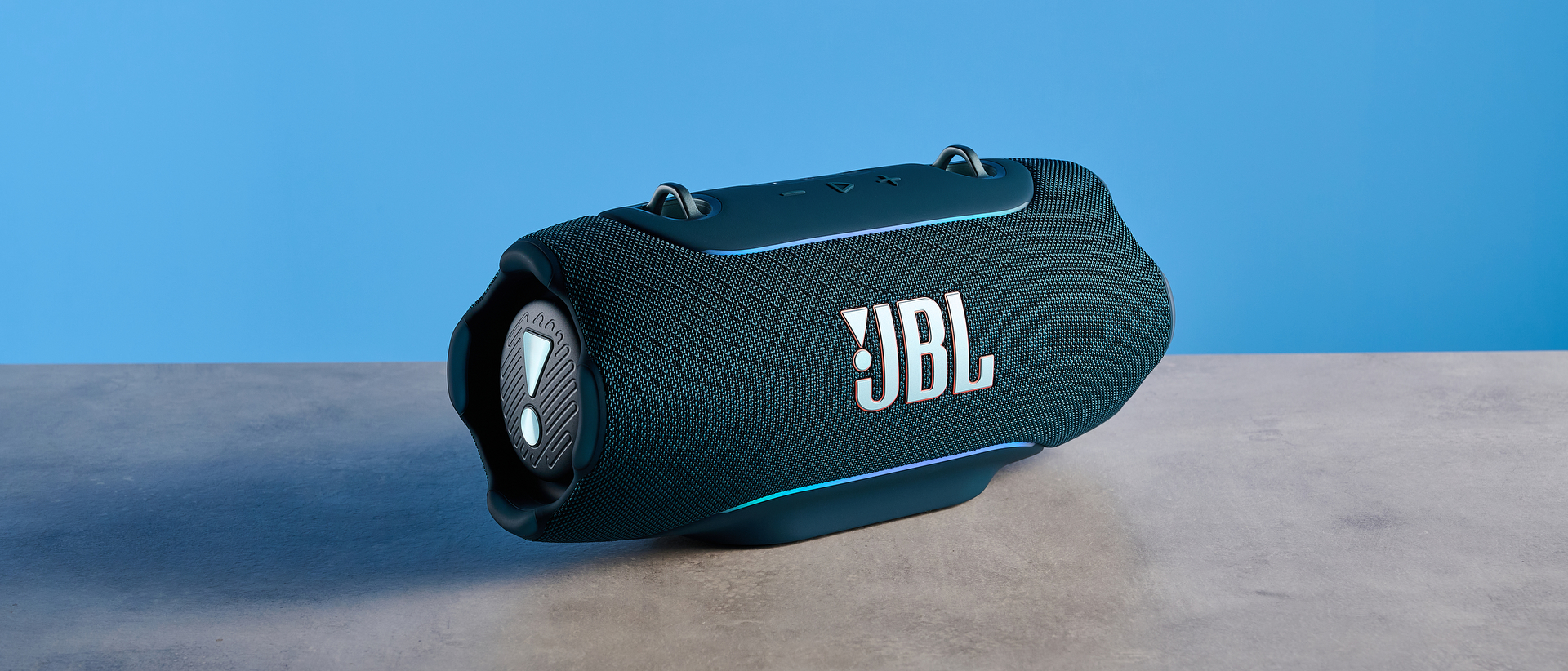the JBL Xtreme 5 bluetooth speaker in blue shown with the rugged carry strap and buttons