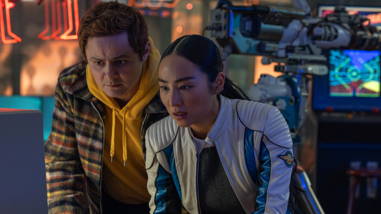 Arturo Castro annd Greta Lee hunch together in a lab setting in Tron: Ares.