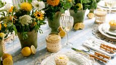 a table setting with potted flowers, bamboo cutlery and lemons
