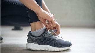 Woman's hands tying up laces on running shoe