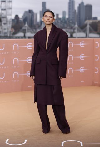 Zendaya wearing a plum suit while attending a Dune: Part Two photocall