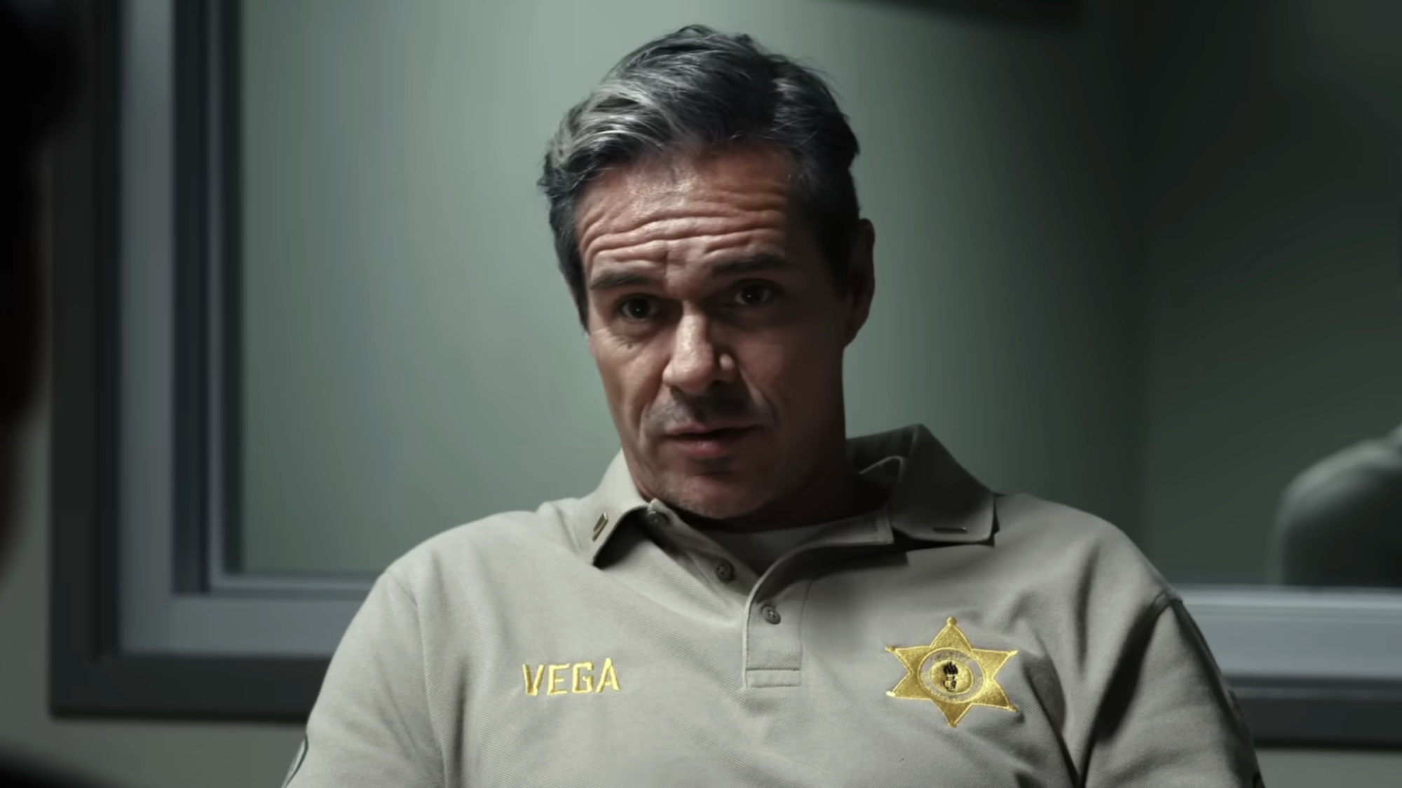 Ray Vega with smug look interrogating John Sugar in police station in Sugar Season 2