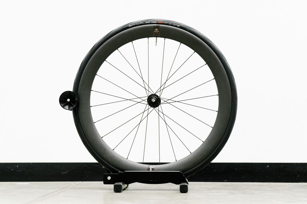 An aero road wheel stands against a white wall