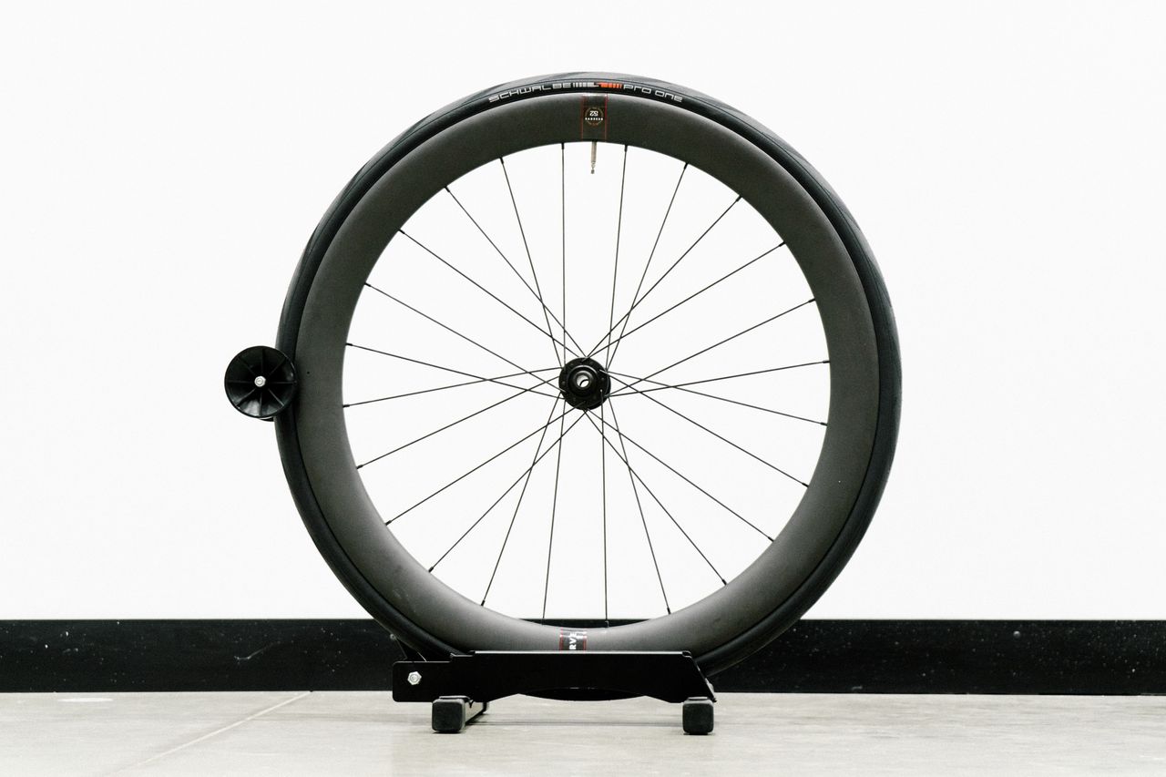 An aero road wheel stands against a white wall