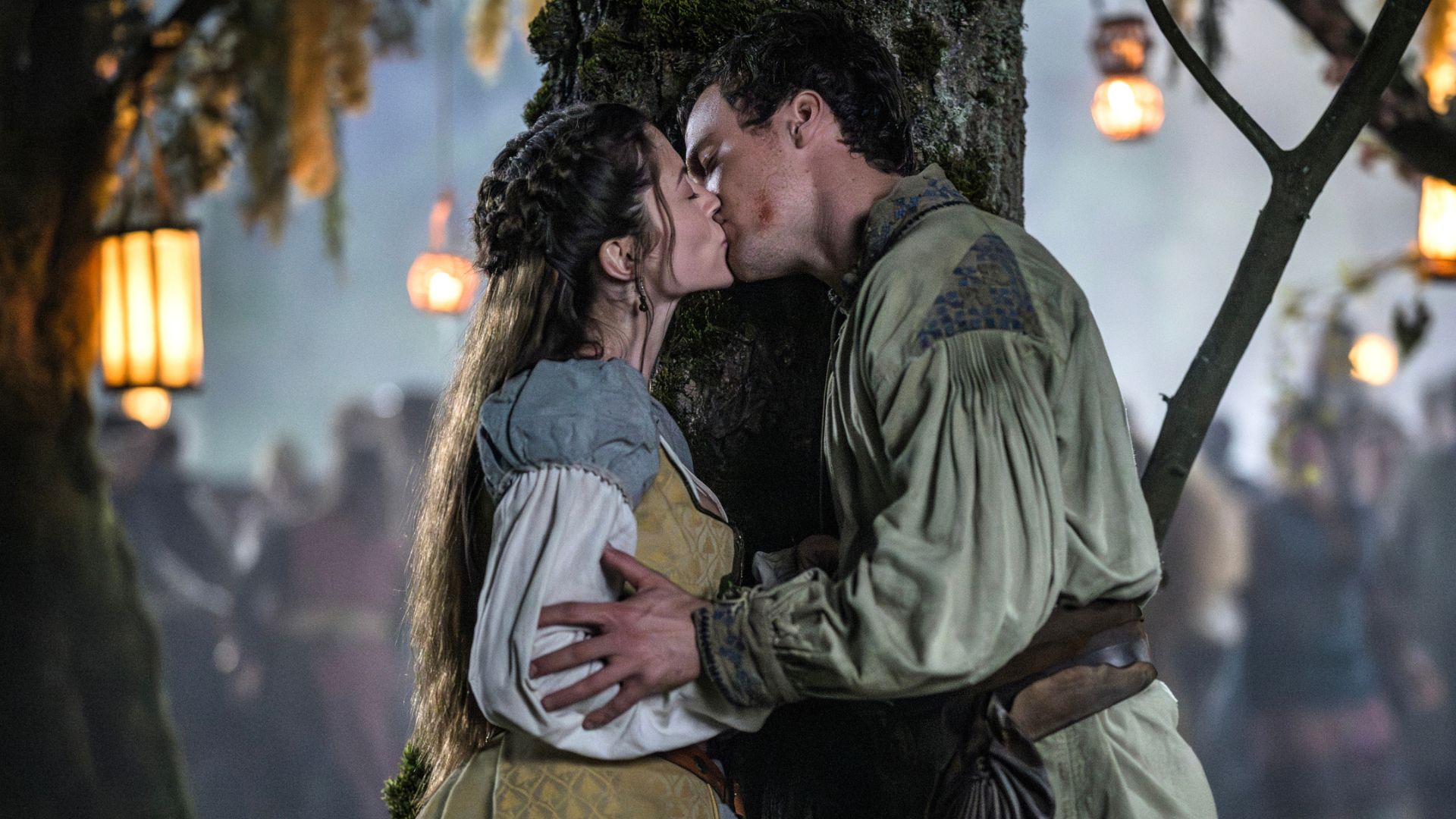 Marian and Rob kiss behind a tree