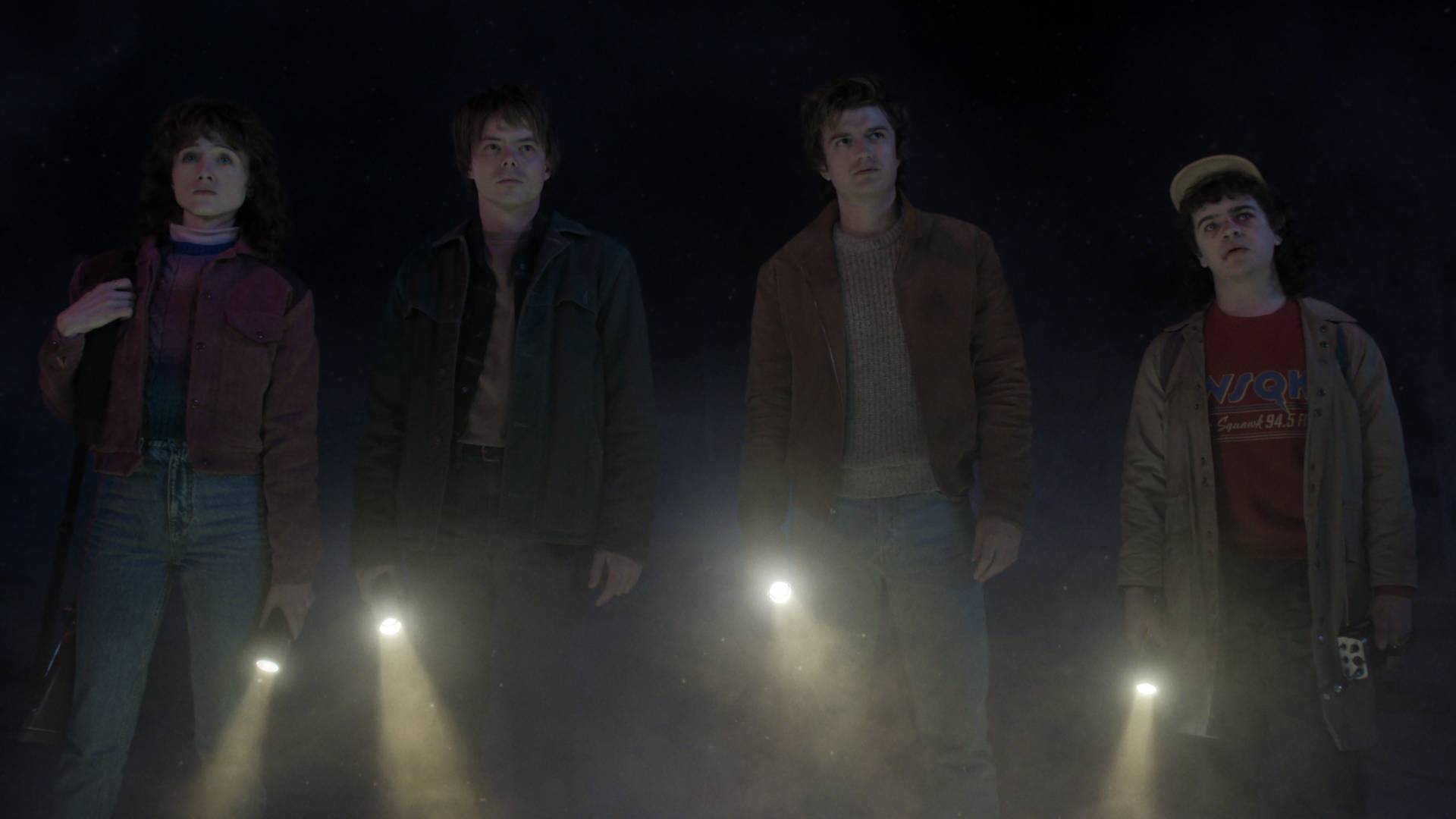 Natalia Dyer as Nancy Wheeler, Charlie Heaton as Jonathan Byers, Joe Keery as Steve Harrington, and Gaten Matarazzo as Dustin Henderson, holding torches in Stranger Things season 5 volume 2