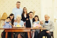 An large family gathers around the grandmother, who has a birthday cake and is turning 81.