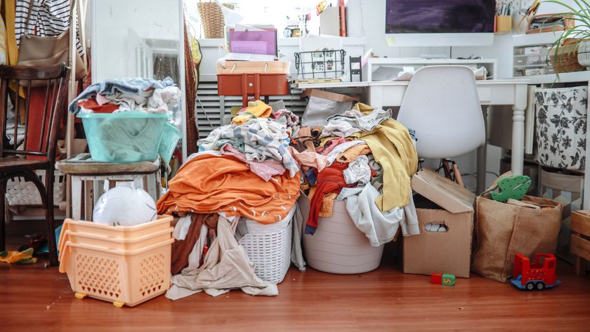 room with baskets of laundry piled up, desk, chair, boxes