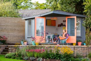 colourful she shed with coral painted doors and desk