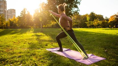 Woman doing 10-minute resistance band workout from yoga mat in sunshine