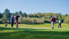 Golfer holing putt in fourball formate