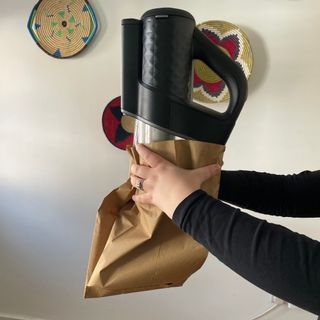 Using a paper bag to catch the contents of a black vacuum cleaner