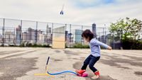 A young girl launching a stomp rocket by stamping on its launcher. 