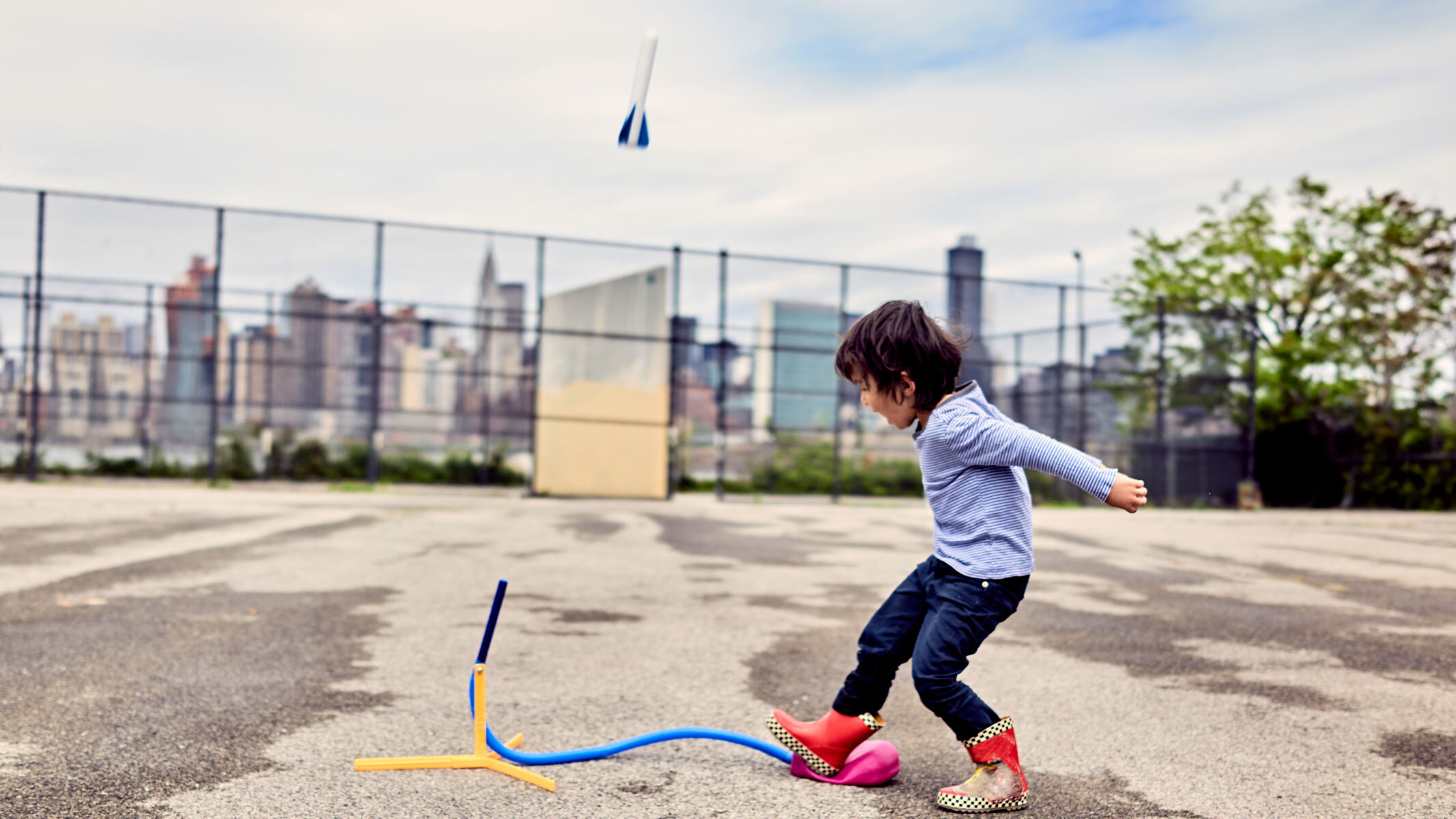A young girl launching a stomp rocket by stamping on its launcher. 