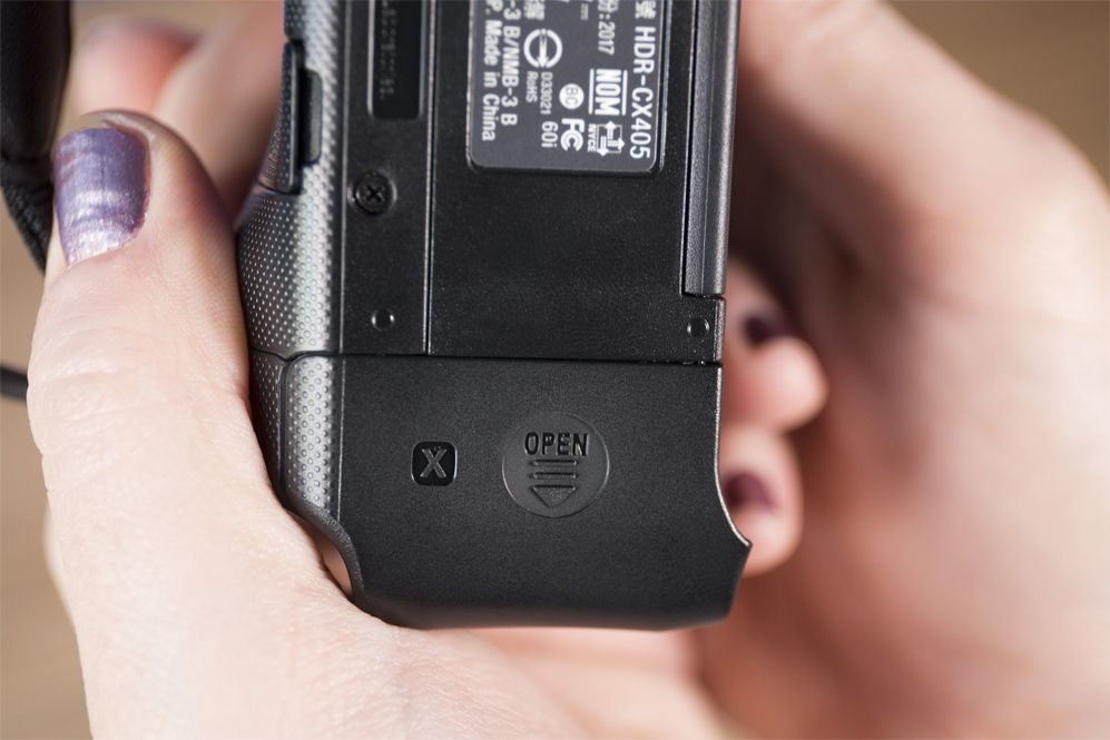 The battery is located at the back of the Sony Handycam HDR-CX405.
