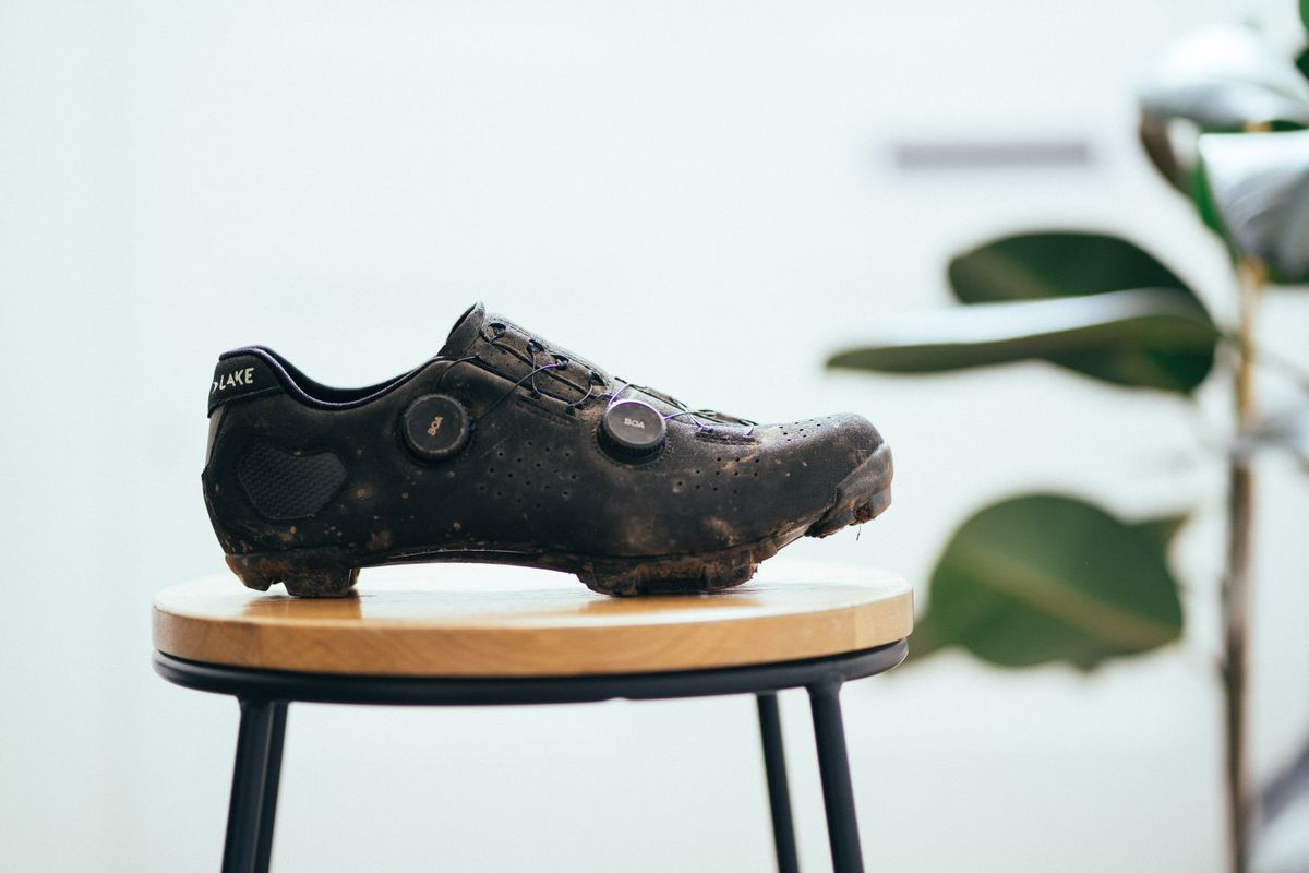 A black gravel shoe on a wooden stool against a white background
