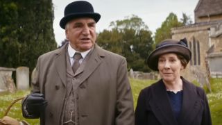 Jim Carter and Phyllis Logan walk through the garden in conversation in Downton Abbey: A New Era.