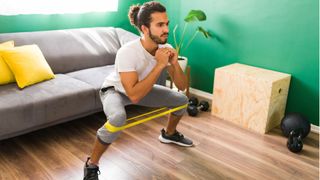 Do resistance bands work? man doing squats with resistance bands