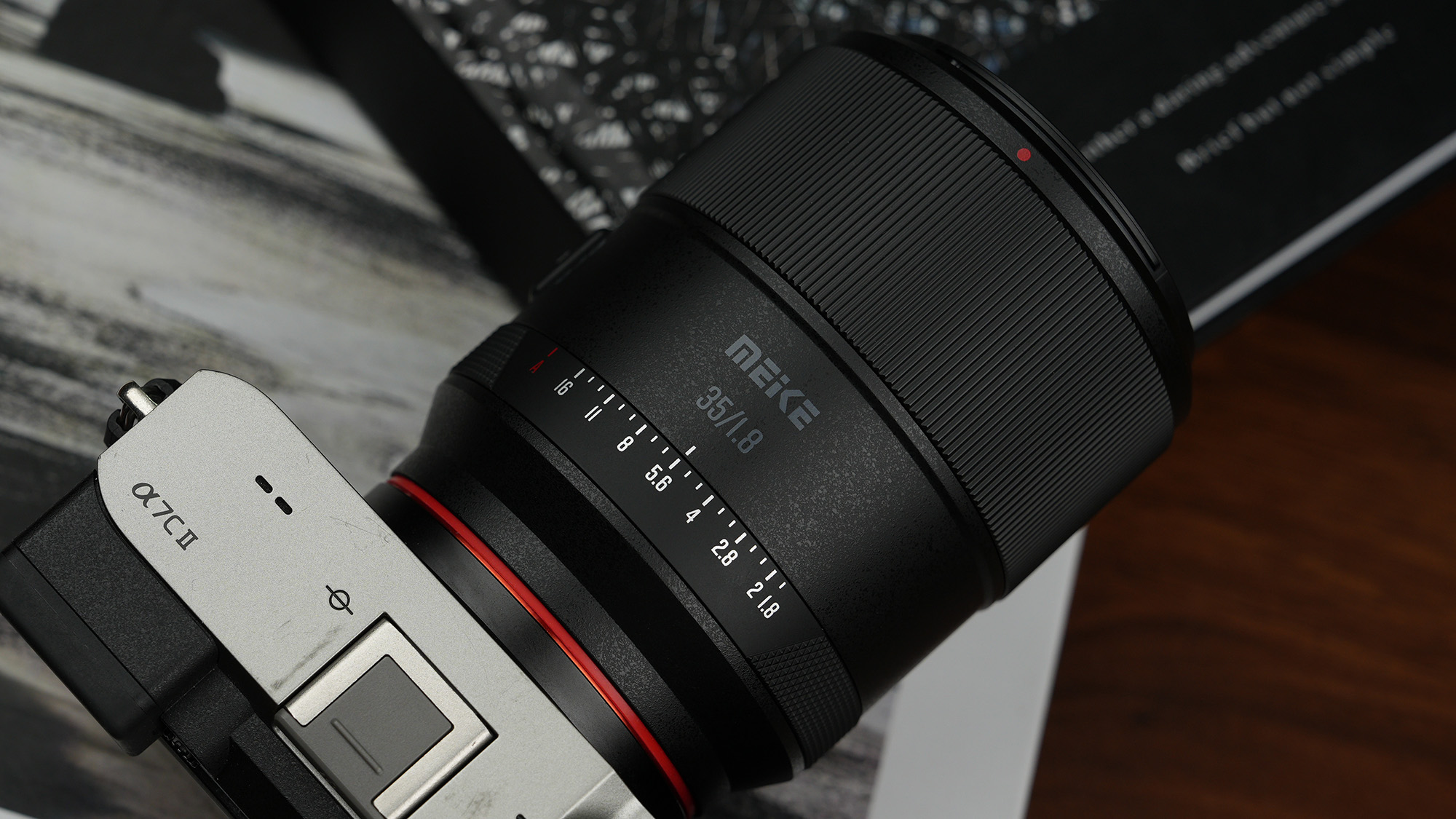 Meike 35mm f/1.8 Pro attached to Sony A7C II camera, resting on a photo book 