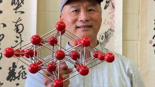 A man holds up a model made of atoms