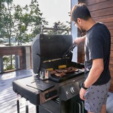 A guy grilling outdoors on a deck