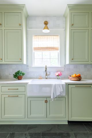 A pale green kitchen with tiles to the ceiling and gold accents