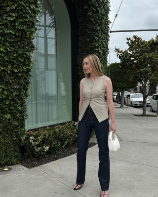 @kristenmarienichols wearing a long-line vest with jeans and strappy sandals.