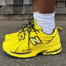 Woman wearing bright yellow New Balance Ganni running sneaker trend.