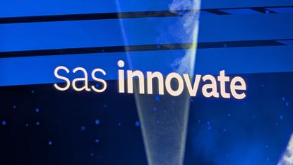 The words 'SAS innovate' on a blue screen at SAS Innovate 2025, with a light beam intersecting the words and highlighting the dry ice in the keynote ballroom.