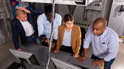 Four adults work together to solve problems in an escape room.