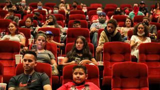 Moviegoers sit in their seats in a crowded theater