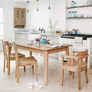 kitchen area with white wall and wooden dining table with chairs