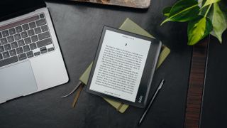 Kobo Sage ereader and its stylus on table beside laptop