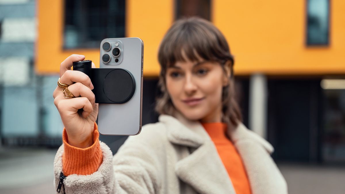 Leica Lux Grip attached to an iPhone held up in a person&#039;s hand as they take a photo